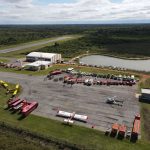Vista aérea de uma base de combate a incêndios florestais, com caminhões, helicópteros e aviões preparados para a operação.