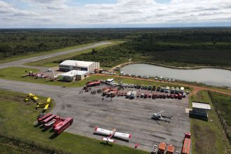 Vista aérea de uma base de combate a incêndios florestais, com caminhões, helicópteros e aviões preparados para a operação.