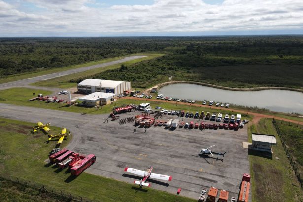 Vista aérea de uma base de combate a incêndios florestais, com caminhões, helicópteros e aviões preparados para a operação.