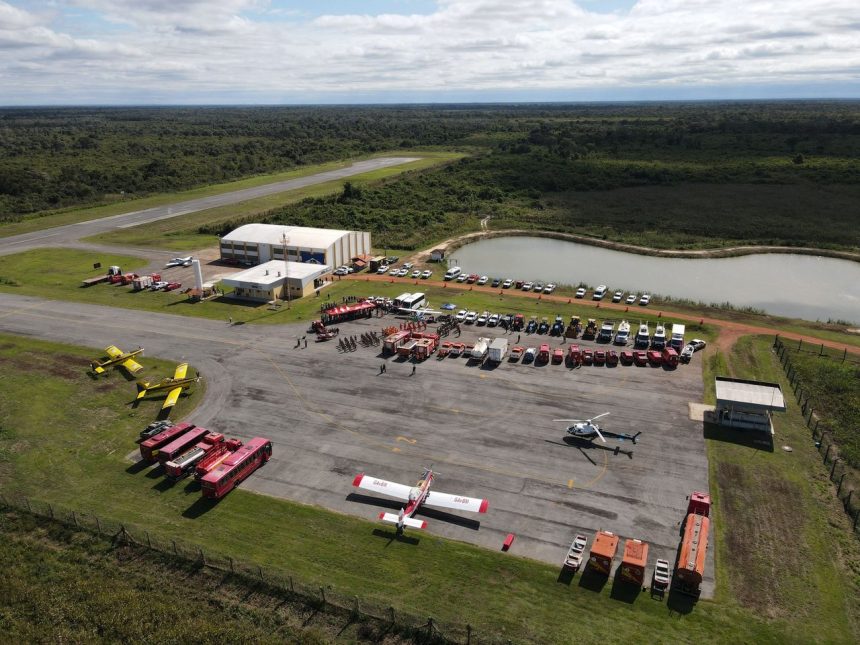 Vista aérea de uma base de combate a incêndios florestais, com caminhões, helicópteros e aviões preparados para a operação.