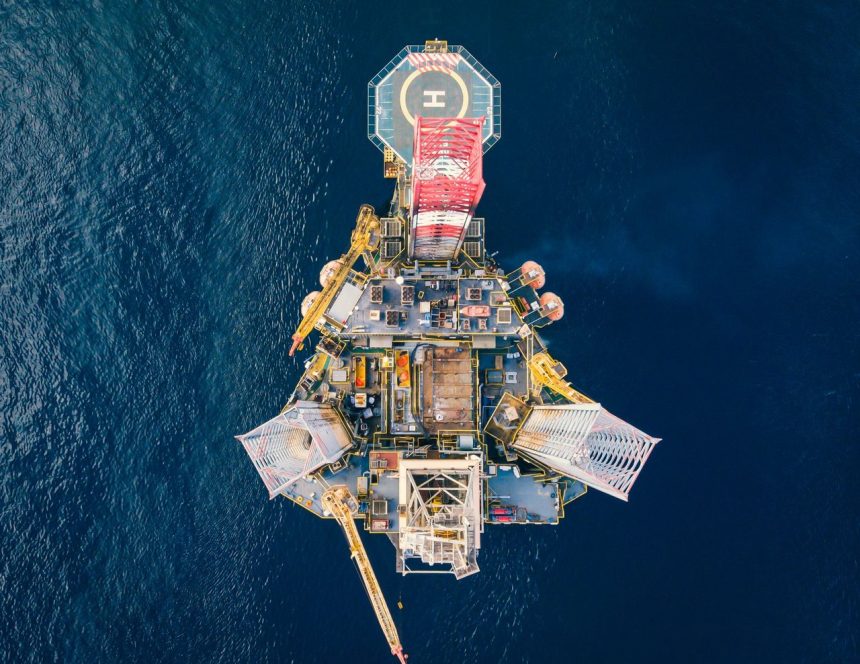 Vista aérea de uma plataforma de petróleo offshore cercada pelo oceano.