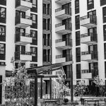 Edifício residencial contemporâneo com varandas e pátio interior, visto a partir da área urbana envolvente.