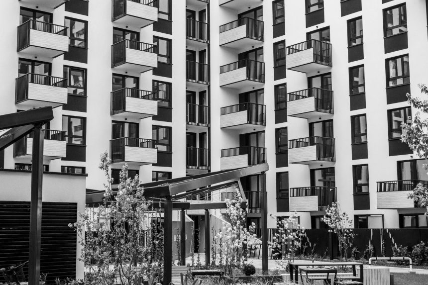 Edifício residencial contemporâneo com varandas e pátio interior, visto a partir da área urbana envolvente.